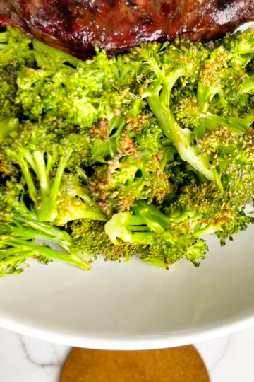 Oven roasted broccoli close up on a white plate.
