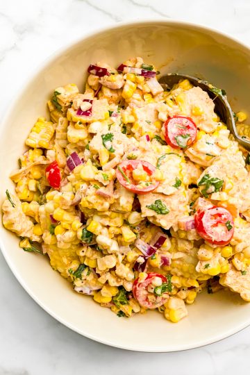 Corn and tomato salad in a beige bowl.